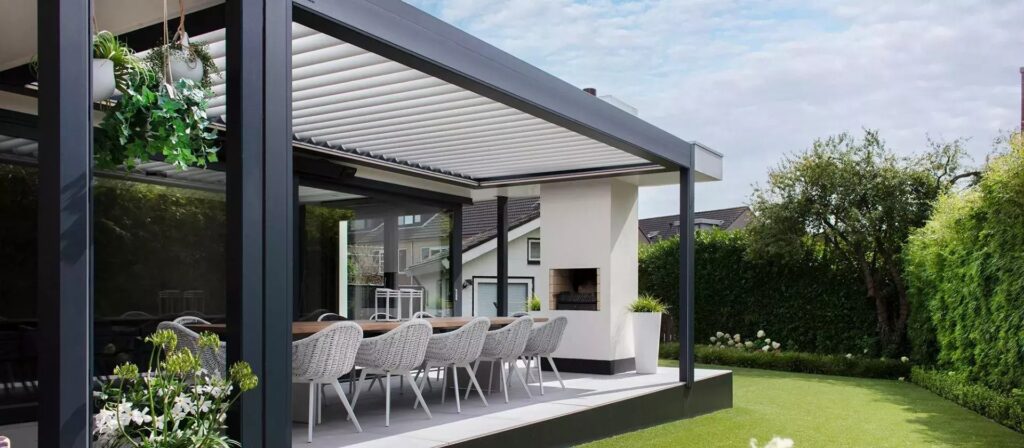 Pérgola bioclimática negra en jardin con mesa y sillas